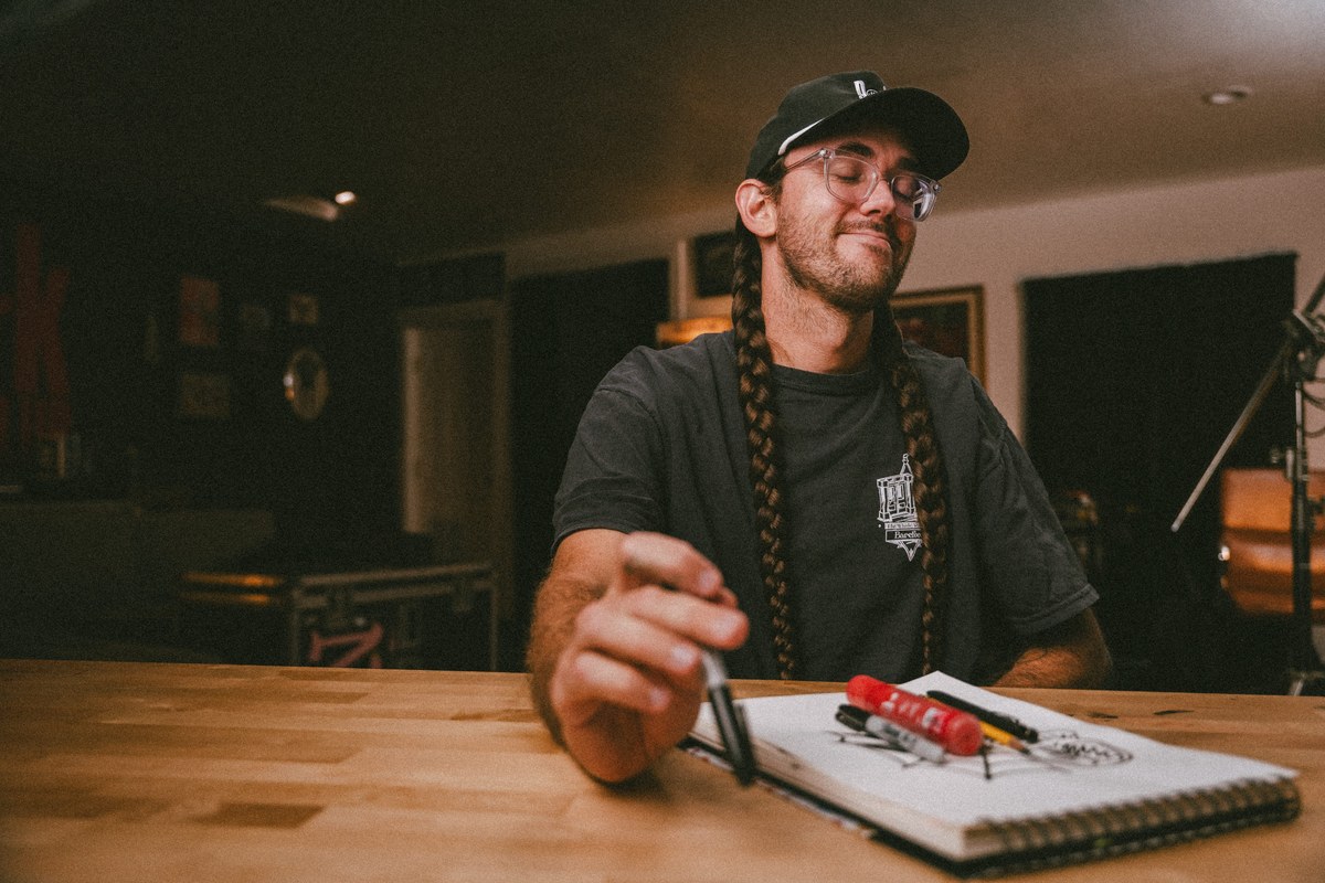 Steven Kinsley of Dork Social Club writing brand notes in a notebook at a wood desk