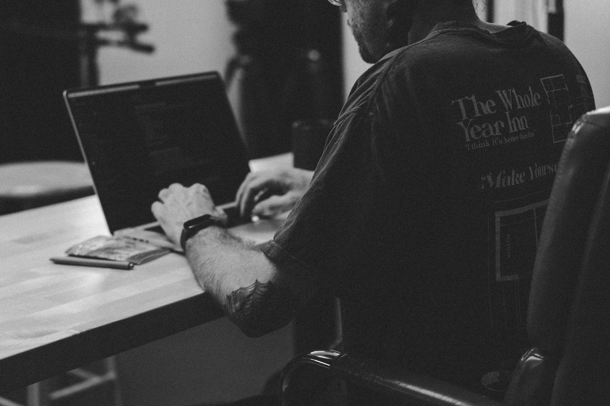 Black and white photo of Steven typing on a laptop at the studio desk